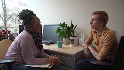 Actors portraying a social worker and client perform a scene used for training purposes.