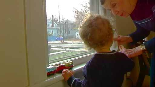 A woman helps her young grandson avoid potential lead hazards by an old window.